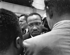 Martin Luther King Jr., who led the procession of mourners at the funeral of Medgar Evers, is confronted by a Mississippi Highway Patrol Officer, 1963, Archival Pigment Print
